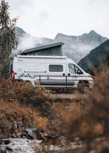 a van parked in a field with mountains in the background