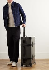 a man in a jacket and pants standing next to a suitcase