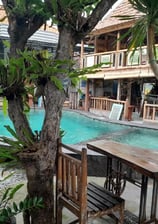 a pool with a wooden table and chairs view in sunrise lodge lovina bali 