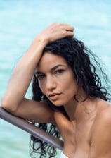 portrait d’une femme au teint doré, regard intense et captivant fixé vers l’appareil photo