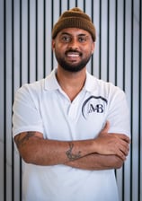 well lit Portrait photo of Maji, Co-owner of MB Barbers Manchester, posing with a smile and his arms crossed