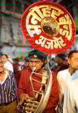 A member of the Manohar Band playing a French horn during a performance.