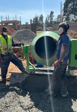 a group of men standing around a cement mixer