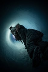 A horror movie poster featuring a woman escaping from a dark ice tunnel, looking in fear behind her