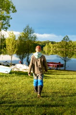 a man walking through a field with boats and boats