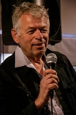 Portrait of an old man speaking on the mic at a networking event