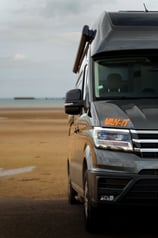 a van parked on the beach with a surfboard