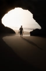 a man walking on the beach with a surfboard . arbab naimat kasi balochistan