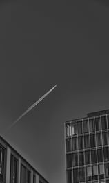 a jet plane flying over a building with a jet plane flying overhead