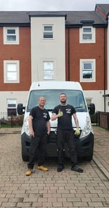 two men standing next to a van 