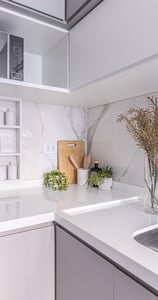 Uma cozinha em tons cinzas com moveis planejados, o design minimalista e elegante conferem um aconchego com o uso de plantas.