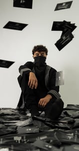 a man in a black shirt and black pants sitting on a pile of black and