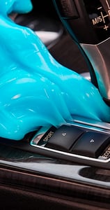 a person in a blue gloved hand held up to a car's dashboard