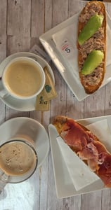 a table with a cup of coffee and a sandwich