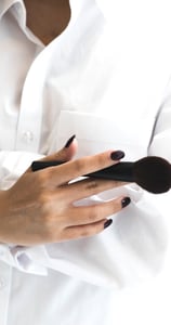 Vrouw met wit hemd en schmink borstel vast 