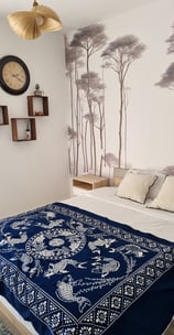 a bed with a blue blanket and a clock on the wall