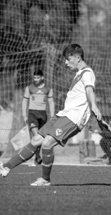a young man kicking a soccer ball in a soccer field