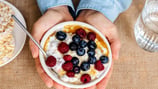 a person holding a bowl of cereal and cereal