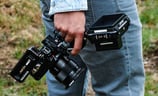 Mann in blauer Jeans, draußen, mit Kamera Rig in der Hand, von hinten