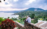 A couple enjoys a romantic moment on a mountaintop overlooking Koh Samui's diverse landscape.