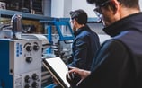 Pracownicy fabryki produkują części metalowe używając maszyny cnc