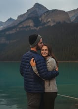 a man and woman standing in front of Lake Louise 