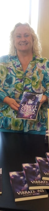 a woman standing in front of a table with booksks and a book