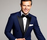 a man in a tuxedo suit and bow tie smiling