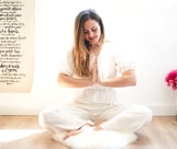 photo of a woman sitting on a rug in a room practising yoga
