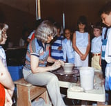 Naoma Powell throwing on the wheel in front of a class of elementary students.