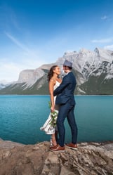 a bride and groom standing on a rock formation