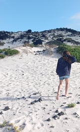 a little girl walking on a white sandy beach with a blue sky in the background