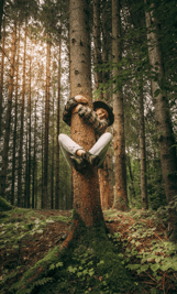 a girl hugging a tree trunk in a forest 