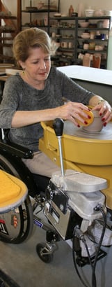 Woman in a wheelchair throwing on our wheelchair-accessible potter's wheel.