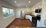 A modern kitchen with white cabinetry, black countertops, and stainless steel appliances