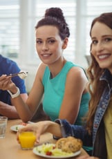 Vrouw zit aan tafel met een bord gezond eten.