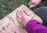 a child's hand holding a small wooden block