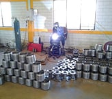 a man welding a metal pipe in a warehouse