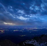 Säntis – Nachtansicht von oben mit Blick auf beleuchtete Städte und Wolken