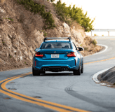 a blue car driving down a curve in the road