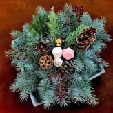 Aranjament de iarnă cu crengi de brad, conuri, bobițe roșii și decorațiuni festive într-un vas.