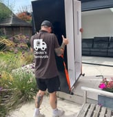 a man in a deanos removals shirt is moving a refrigerator