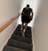 a man from deanos removals walking up a flight of stairs with a box