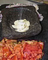 ail et sel dans un pilon avec des tomates coupées