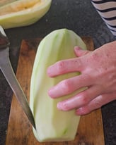 papaye verte avec un couteau et une main