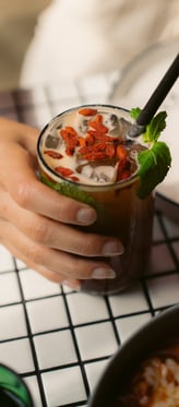 a person holding a drink in a glass