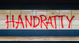 a subway station with “HANDRATTY” graffiti on the wall