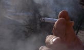 main qui tient une cigarette allumée