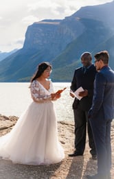 Bride and groom sawing vows in front of a mountain during their Banff elopement