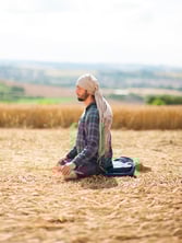 Un homme assis méditant, en pleine conscience, dans la un champ de blé